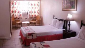 Quarto de hotel com duas camas, uma mesa e uma cadeira.