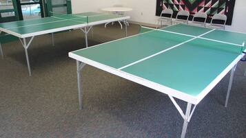 Une pièce où se trouvent quatre tables de ping-pong vertes, disposées en rangée.