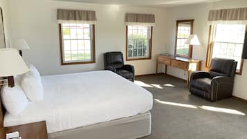 Habitación de hotel con una cama grande, dos sillas, un escritorio y una lámpara.