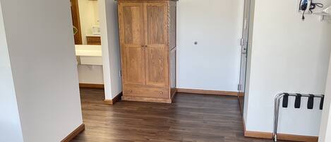 A hallway with wooden flooring, a wooden wardrobe, and a metal rack.