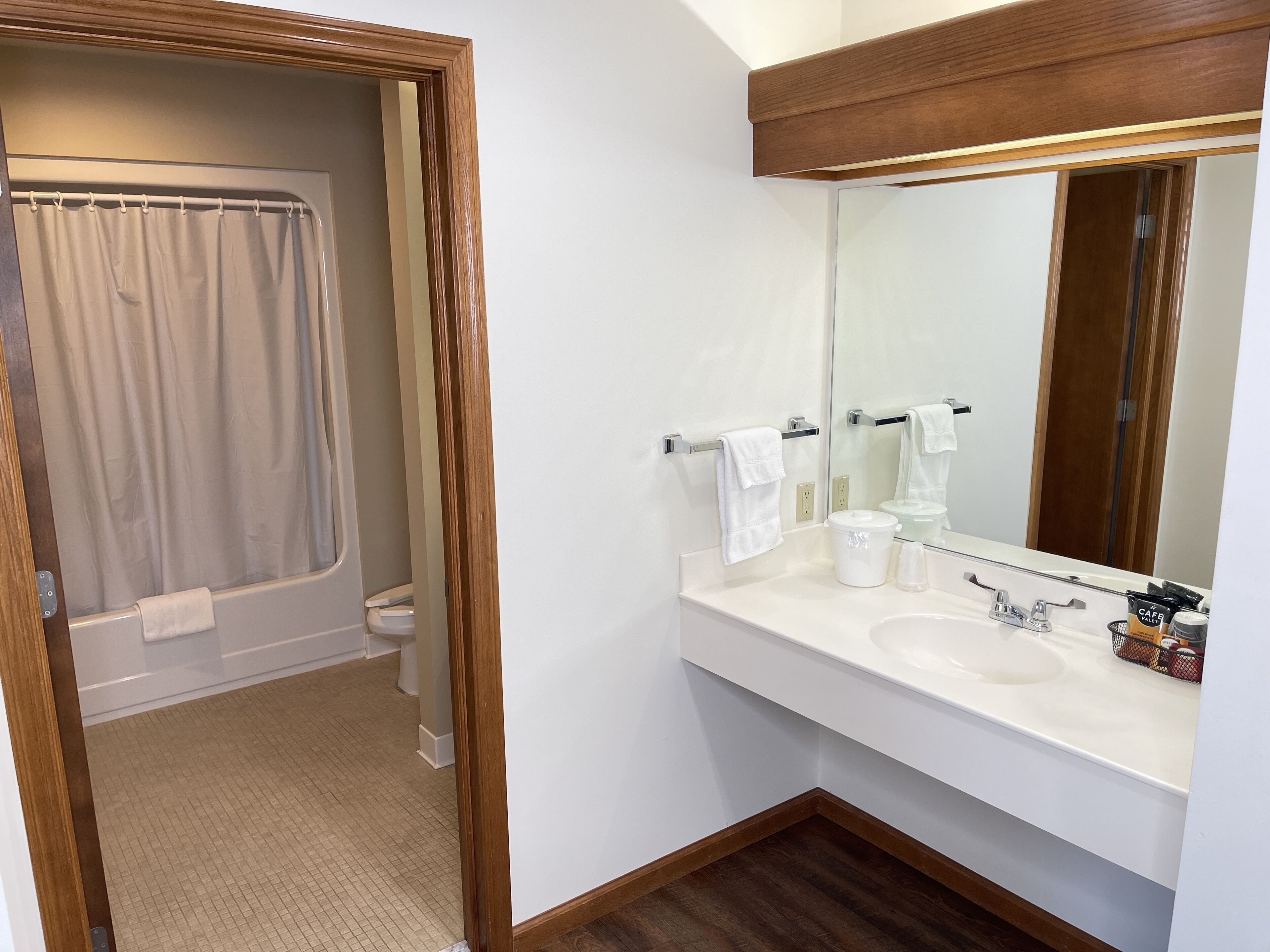A bathroom with a shower, toilet, sink, and mirror.
