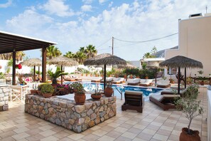 Un espace aménagé au bord de la piscine, avec des chaises longues, des parasols et des plantes en pot.