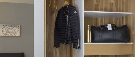 A modern room with a wooden wardrobe, a black jacket, a black handbag, and a water bottle.