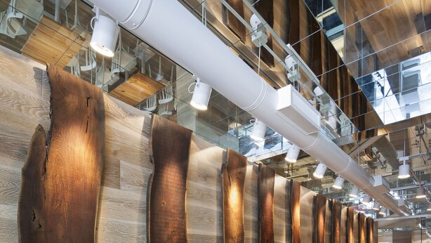 Un interior moderno con piso de madera y una pared con paneles de madera de formas irregulares.
