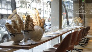 Un restaurante con una barra larga, sillas y una exhibición de pan.