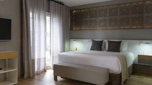 Un dormitorio moderno con una cama grande, una mesita de noche, un televisor y un ventanal con cortinas.