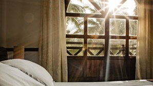 A bedroom with a large window, a bed, and curtains.