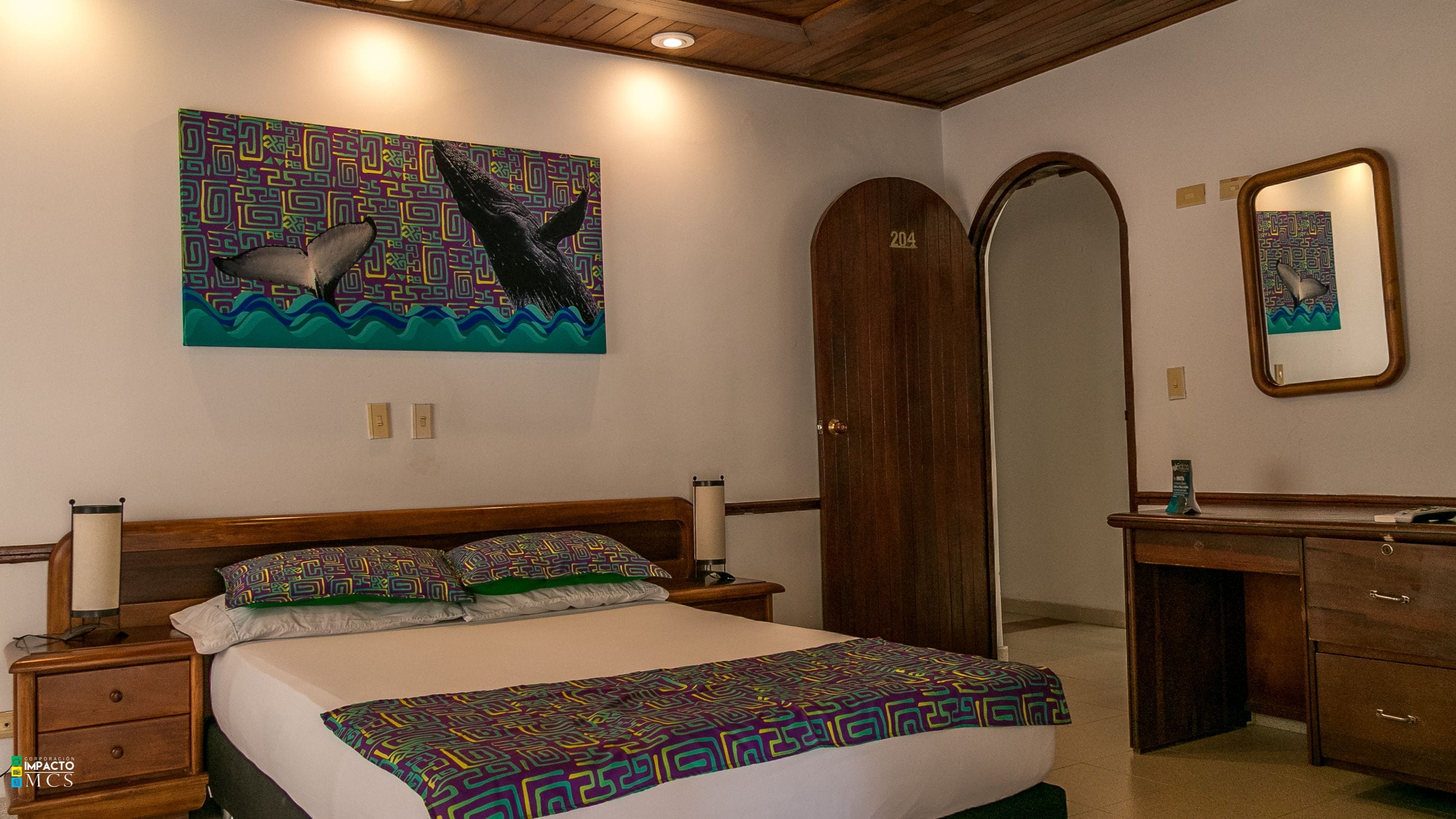 Een slaapkamer met een bed, nachtkastjes, een dressoir, een spiegel en een muur met een kleurrijk abstract schilderij.
