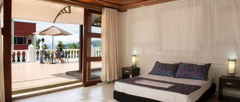 Une chambre d’hôtel avec un lit, des tables de chevet et une vue sur la terrasse extérieure.