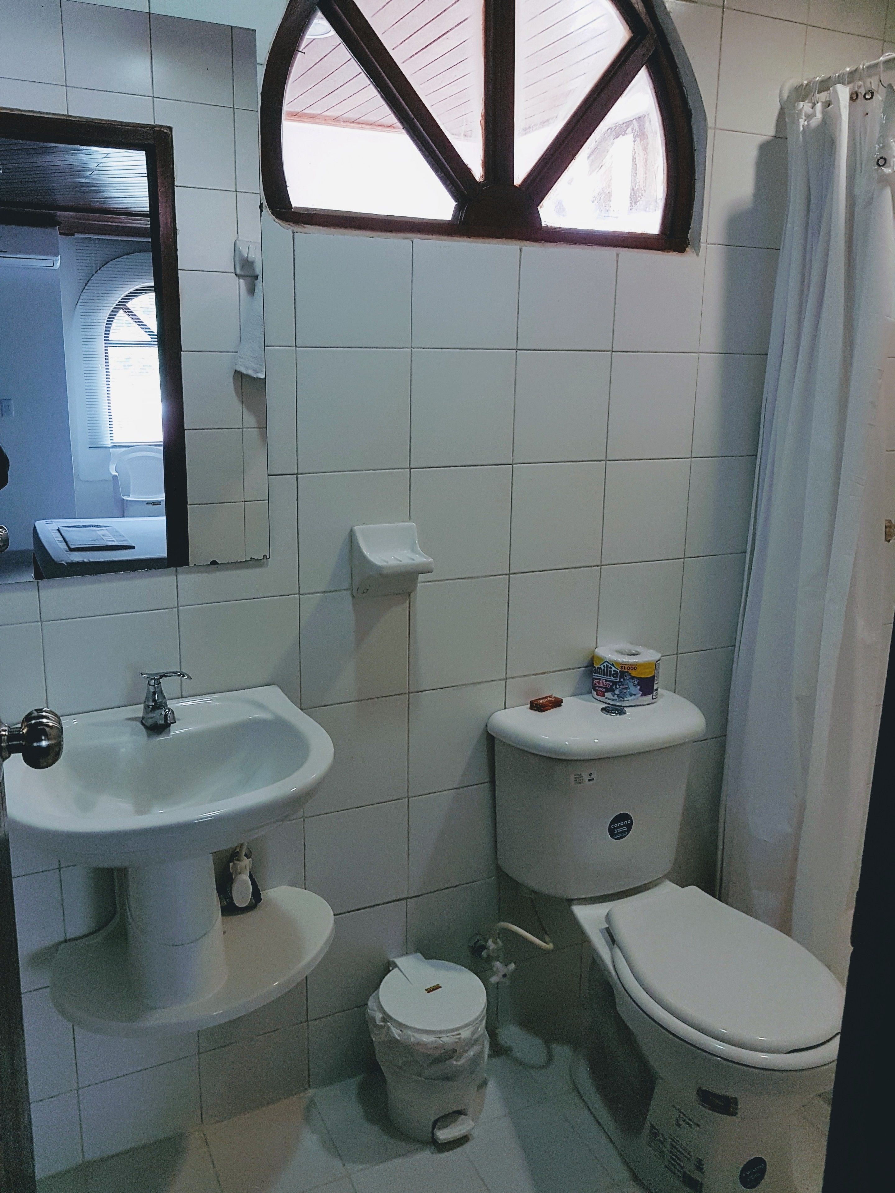 Un bagno con lavandino, water e una finestra sopra il water.