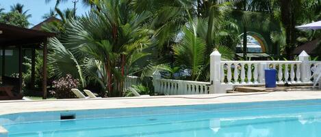 Una piscina al aire libre, sombrillas, sillones reclinables de piscina