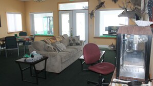 A living room with a sofa, a red office chair, a table with a lamp, and a vintage radio.
