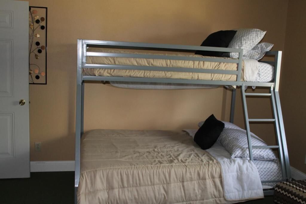 A bunk bed with a ladder, a door, and a wall decoration.
