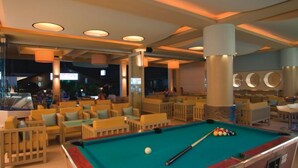 A pool area with multiple seating arrangements, a pool table, and overhead lighting. - Stalis Hotel (Hersonissos)
