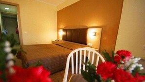 A hotel room with a bed, bedside table, and a chair. - Orpheus (Komotini)