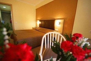 Ein Hotelzimmer mit Bett, Nachttisch und einem Sessel.