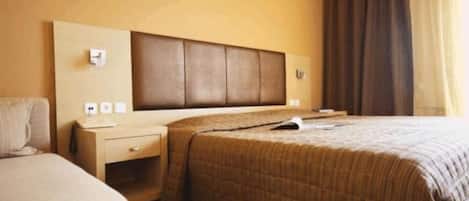 Una habitación de hotel con cama, mesita de noche y un equipo de aire acondicionado instalado en la pared.