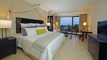A hotel room with a large bed, a desk, a chair, a TV, and a balcony with a view.