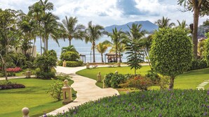 A well-maintained garden with a pathway leading to a gazebo, surrounded by palm trees and a view of the sea. - Dreams Playa Bonita Panama - All Inclusive (Veracruz)