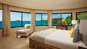 A hotel room with a large bed, a chair, a desk, and a view of the ocean. - Dreams Playa Bonita Panama - All Inclusive (Veracruz)
