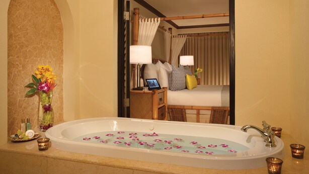 A bathroom with a bathtub, a mirror, and a vanity with toiletries.