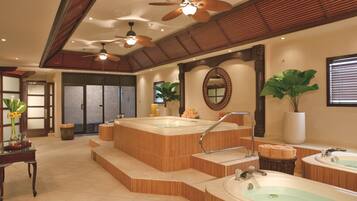 A spa area with multiple hot tubs, wooden steps, ceiling fans, and a large mirror.
