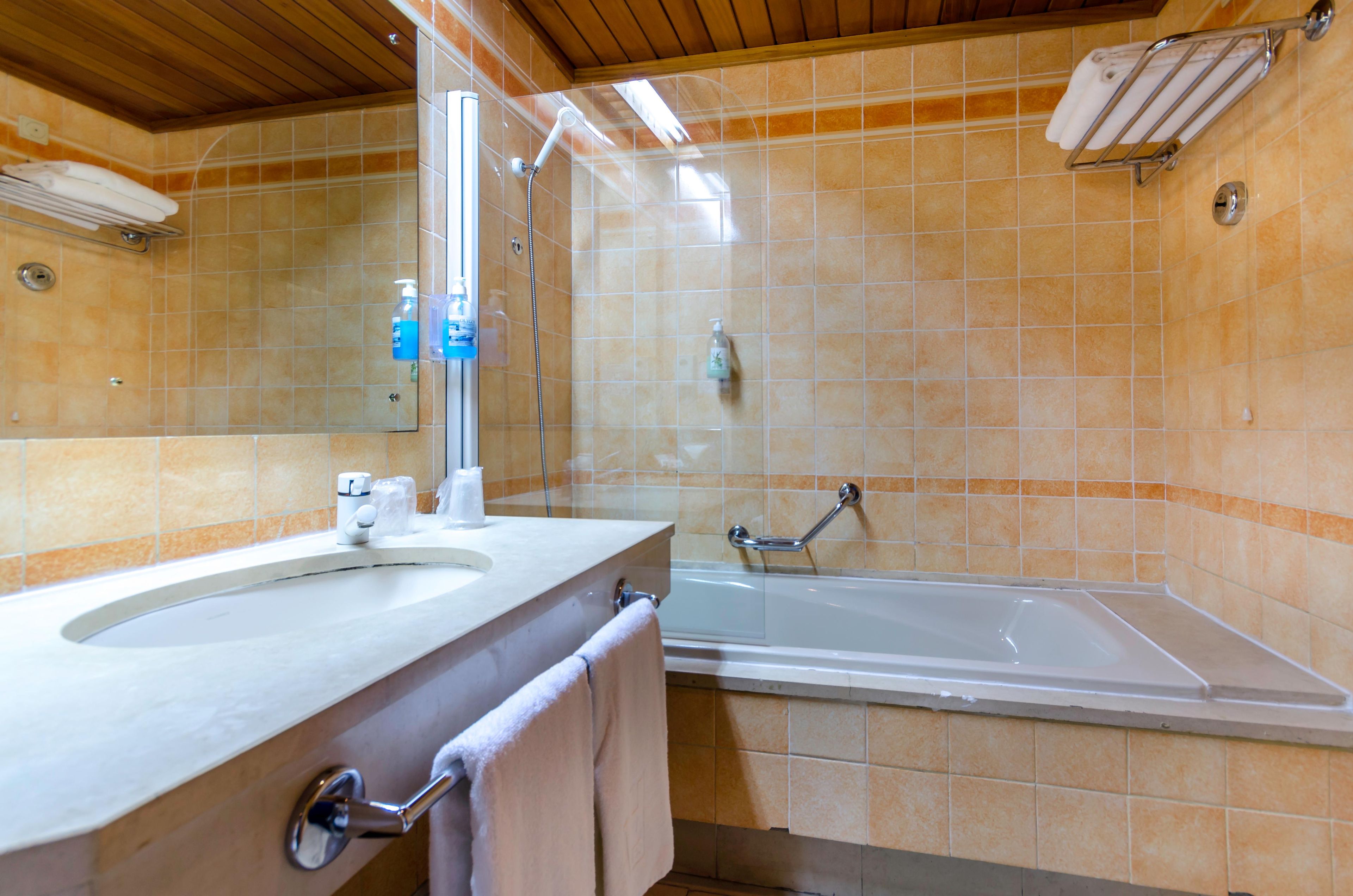 A bathroom with a sink, mirror, and bathtub.