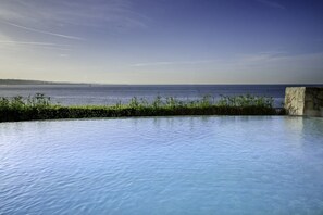 A clear view of a swimming pool with a stone structure on the right and a view of the sea. - The Boutique Hotel Solar Palmeiras (Oeiras)