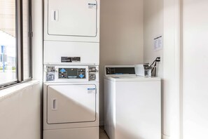 A laundry area with stacked washers and dryers, a window, and a wall-mounted sign. - Motel 6 Tremonton, UT (Tremonton)