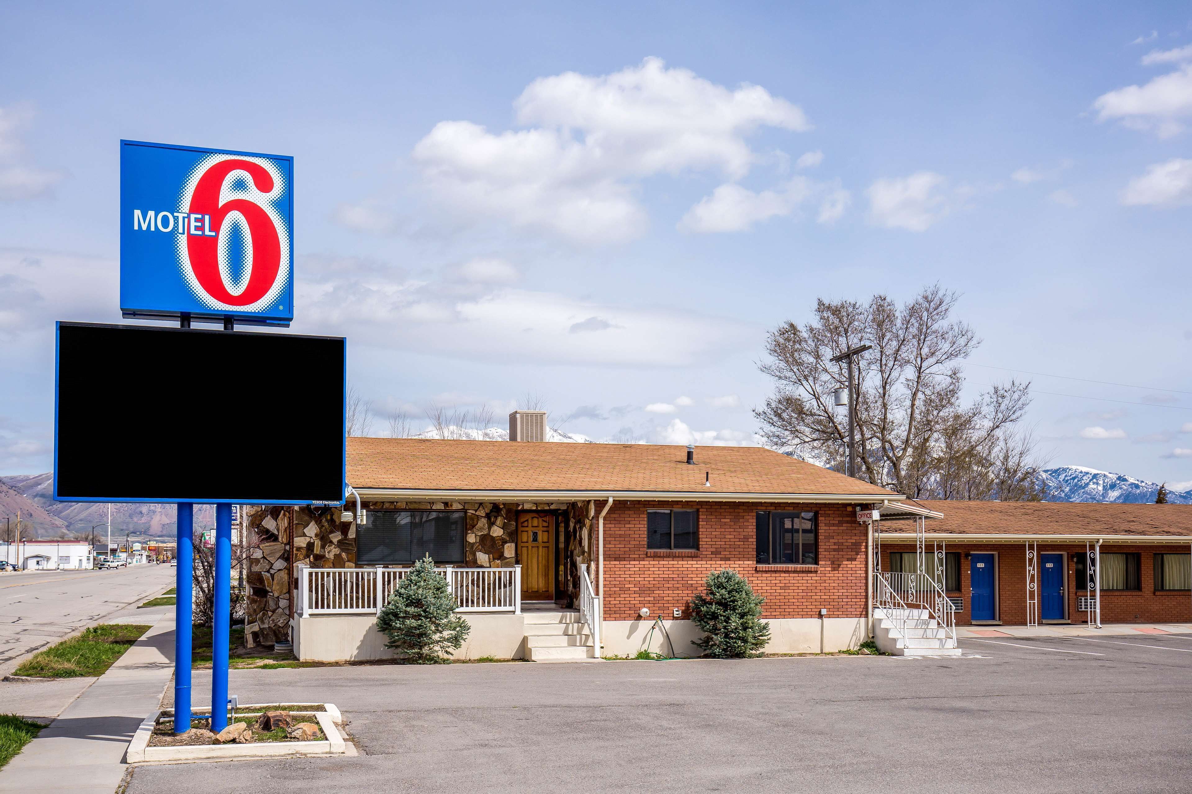 A motel with a prominent '6 Motel' sign, a brick building with a stone facade, and a parking lot.