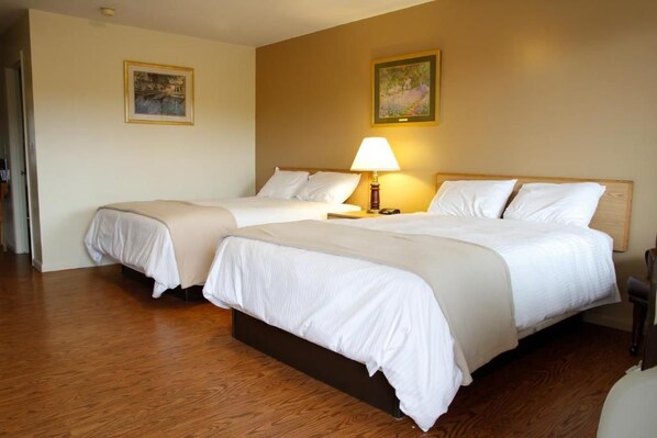 A hotel room with two beds, a wooden floor, and a lamp on the nightstand. - Motel 6 Tremonton, UT (Tremonton)