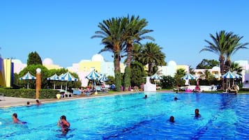 Guests can swim and relax by the pool surrounded by palm trees and striped umbrellas.
