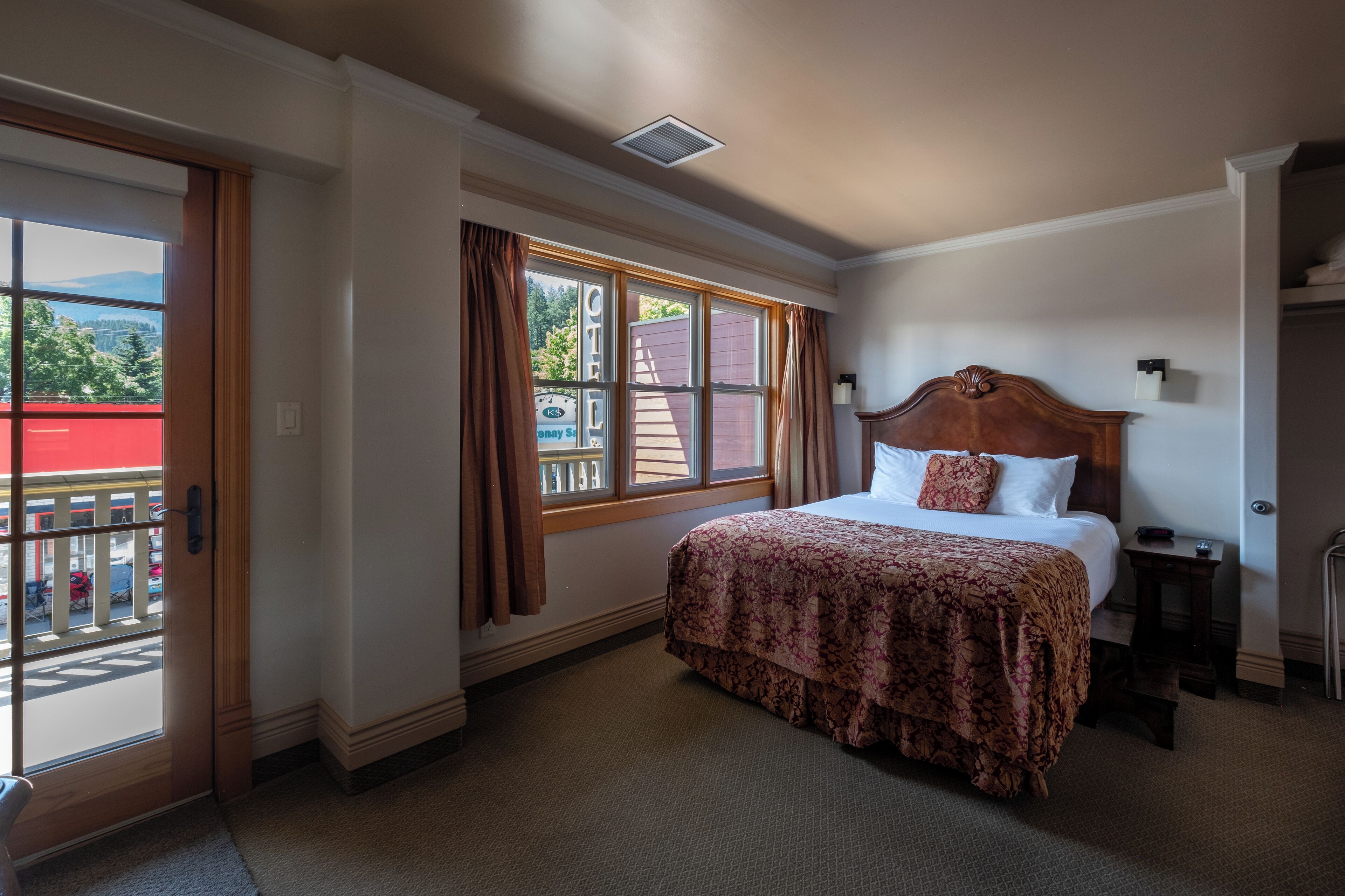Une chambre d’hôtel avec un lit, une fenêtre avec des rideaux, une porte et une vue sur l’extérieur.