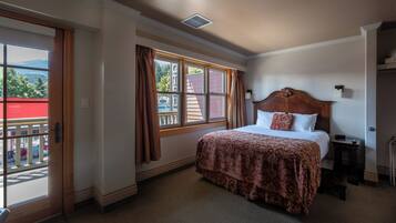 Une chambre d’hôtel avec un lit, une fenêtre avec des rideaux, une porte et une vue sur l’extérieur.