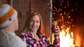 Una persona sosteniendo una bebida frente a una chimenea.