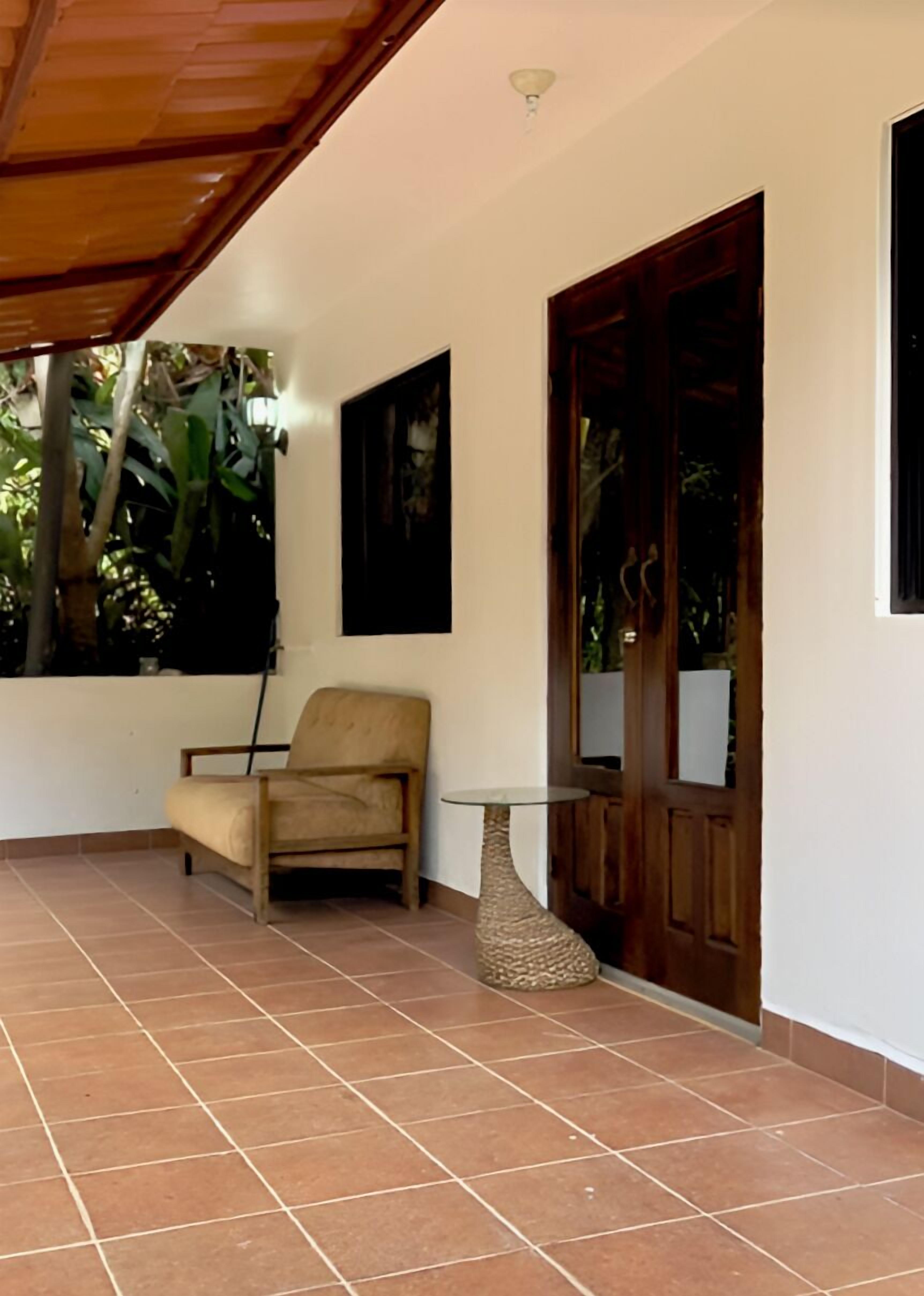 A room with a tiled floor, a wooden chair, a small round table, and a wooden door.