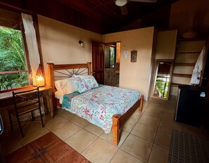 Un dormitorio con cama de madera, un escritorio con lámpara y vistas a la vegetación.