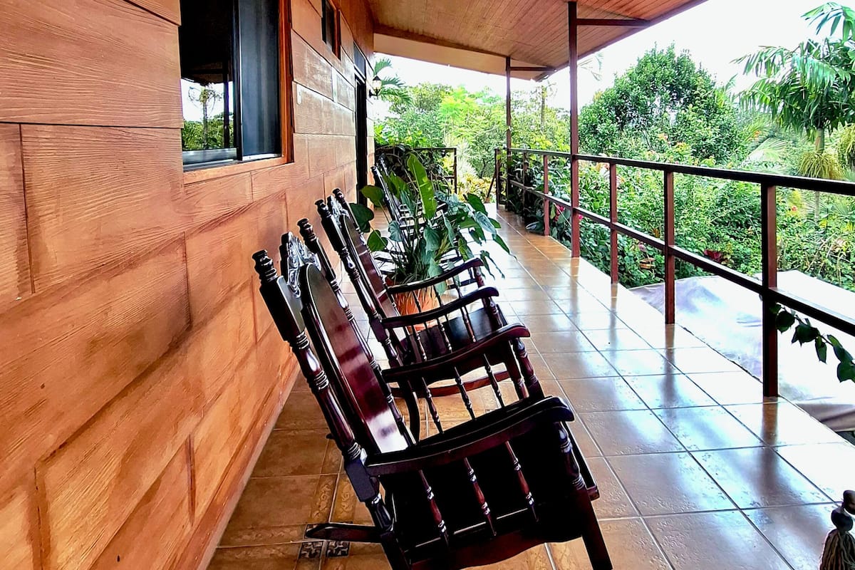 A covered outdoor seating area with wooden benches and a tiled floor.