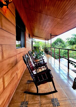 A covered outdoor seating area with wooden benches and a tiled floor. - Eden Atenas (Mercedes)