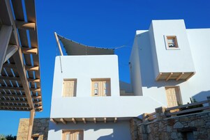 A white building with multiple windows and a stone wall base.