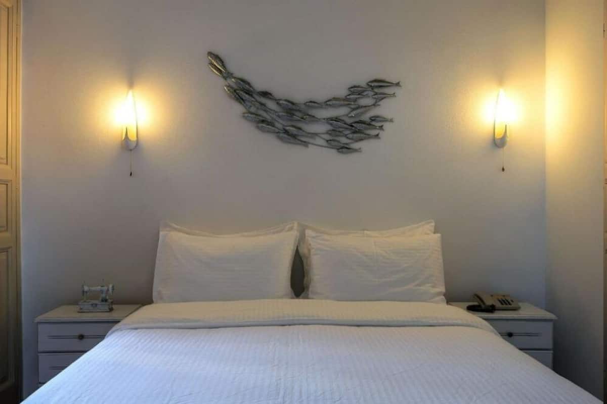Une chambre d’hôtel comprenant un lit, deux tables de chevet, un luminaire fixé au mur et un élément décoratif mural.