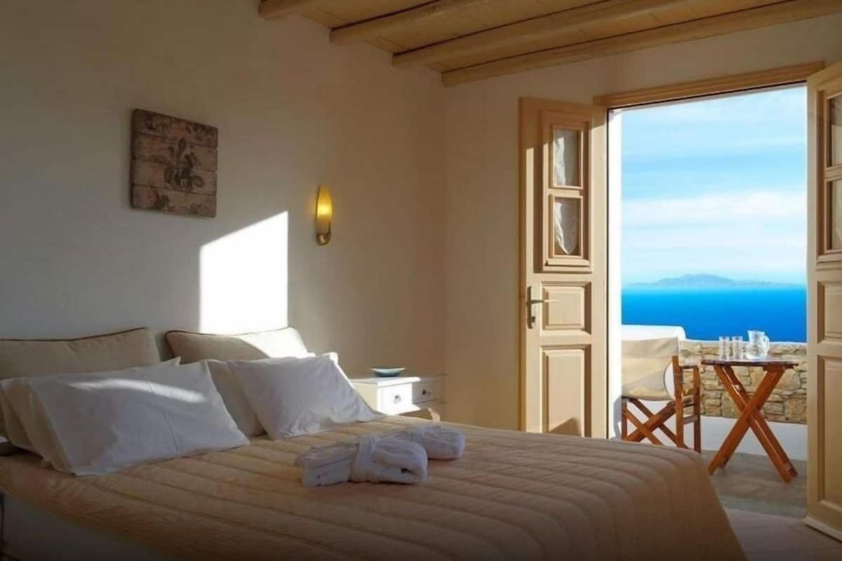 Une chambre à coucher avec un lit, une table de chevet, une table avec des chaises et une vue sur la mer.