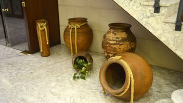 Macetas de terracota con cuerdas enrolladas, sobre un suelo de mármol cerca de una escalera.