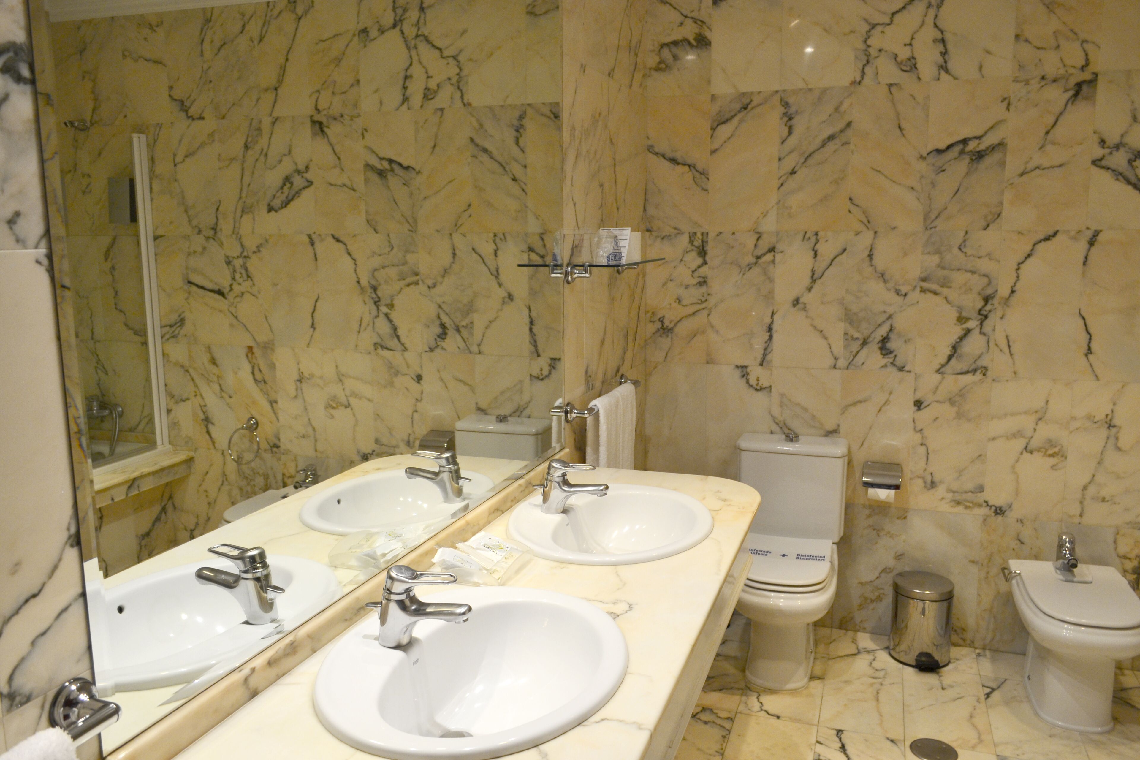 A bathroom with two sinks, a toilet, and a bidet.