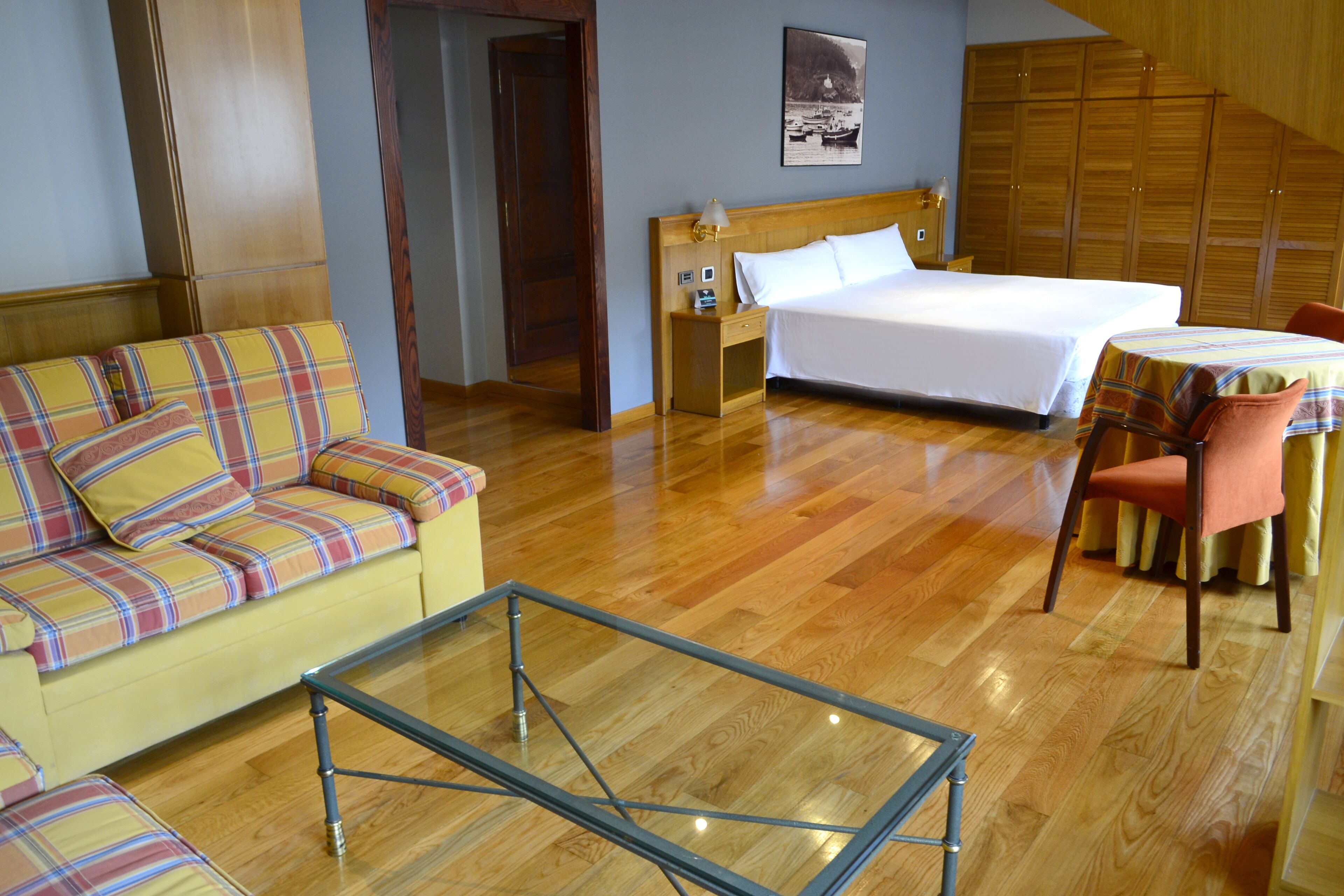 Una habitación de hotel con cama, sofá, mesa y una silla.