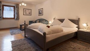 A bedroom with a bed, bedside tables, a window with curtains, and wall-mounted artwork.