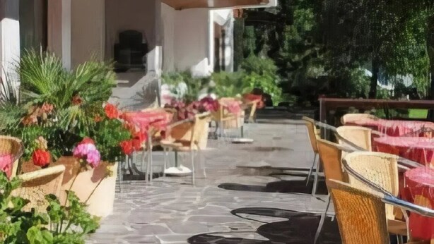 An outdoor seating area with stone flooring and wicker chairs.