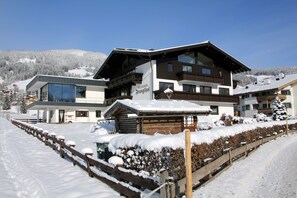 A modern ski resort building with a large glass entrance, wooden exterior, and a sign reading "Pension Franglhof". - Pension Franglhof (Kirchberg in Tirol)