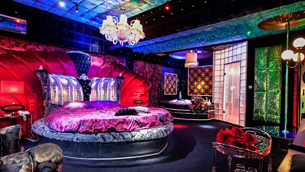 A luxurious bedroom with a large bed, a chandelier, and a decorative wall. - Priamos - Adults Only (Athens)