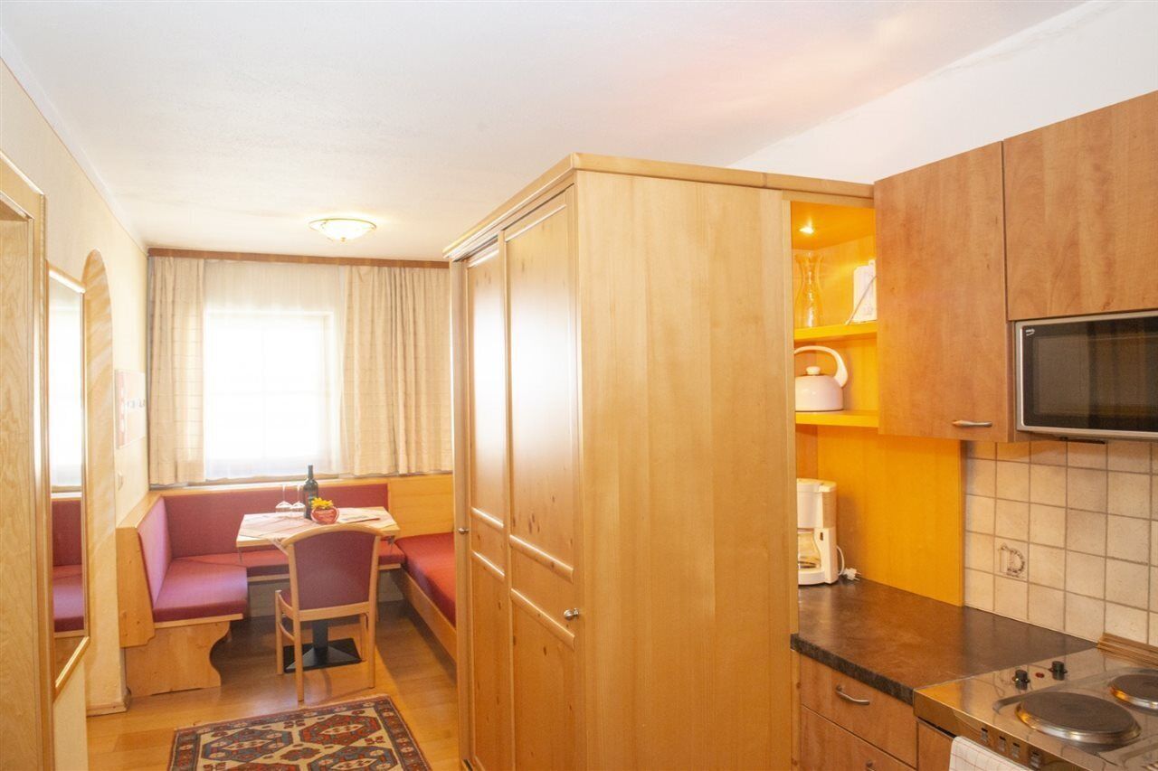 Una cocina compacta con armarios de madera, microondas y zona de comedor con mesa y bancos.